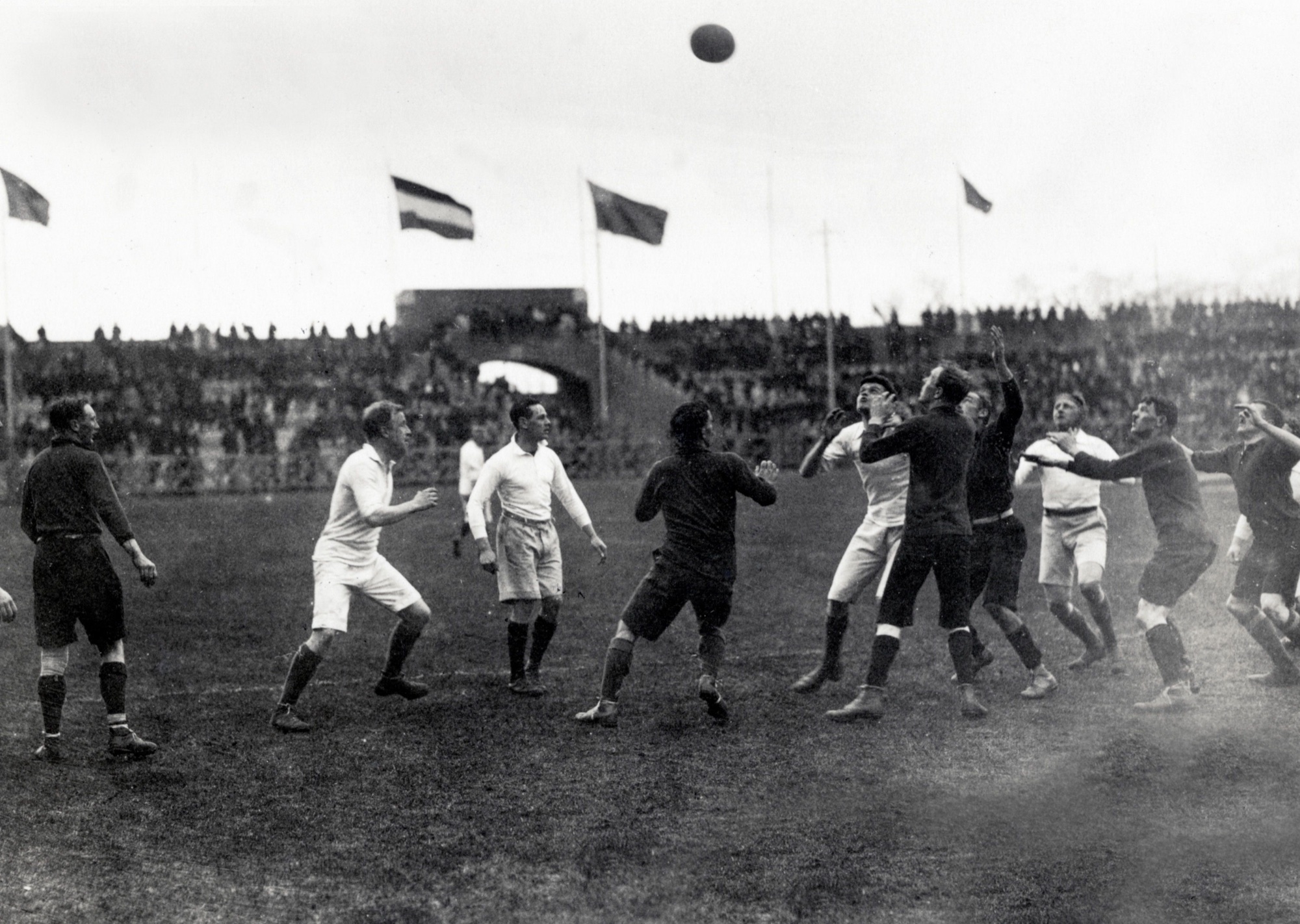 Black-and-white photograph from 1918 of British internees contesting a rugby line-out at Stadion Amsterdam, with the ball high above the players and spectators filling the stands.