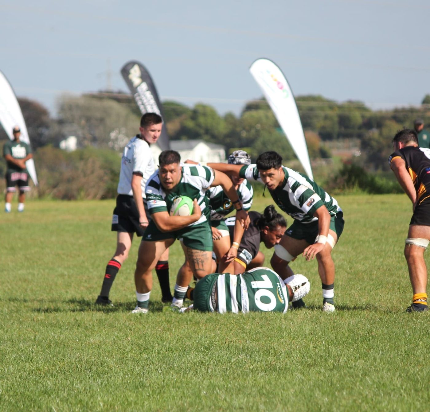 A ball-carrier in green-and-white hoops breaks away from a breakdown with team-mates in support