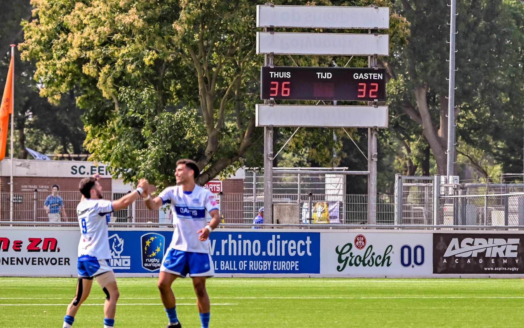AAC players celebrating in front of the pitchside sponsor boards