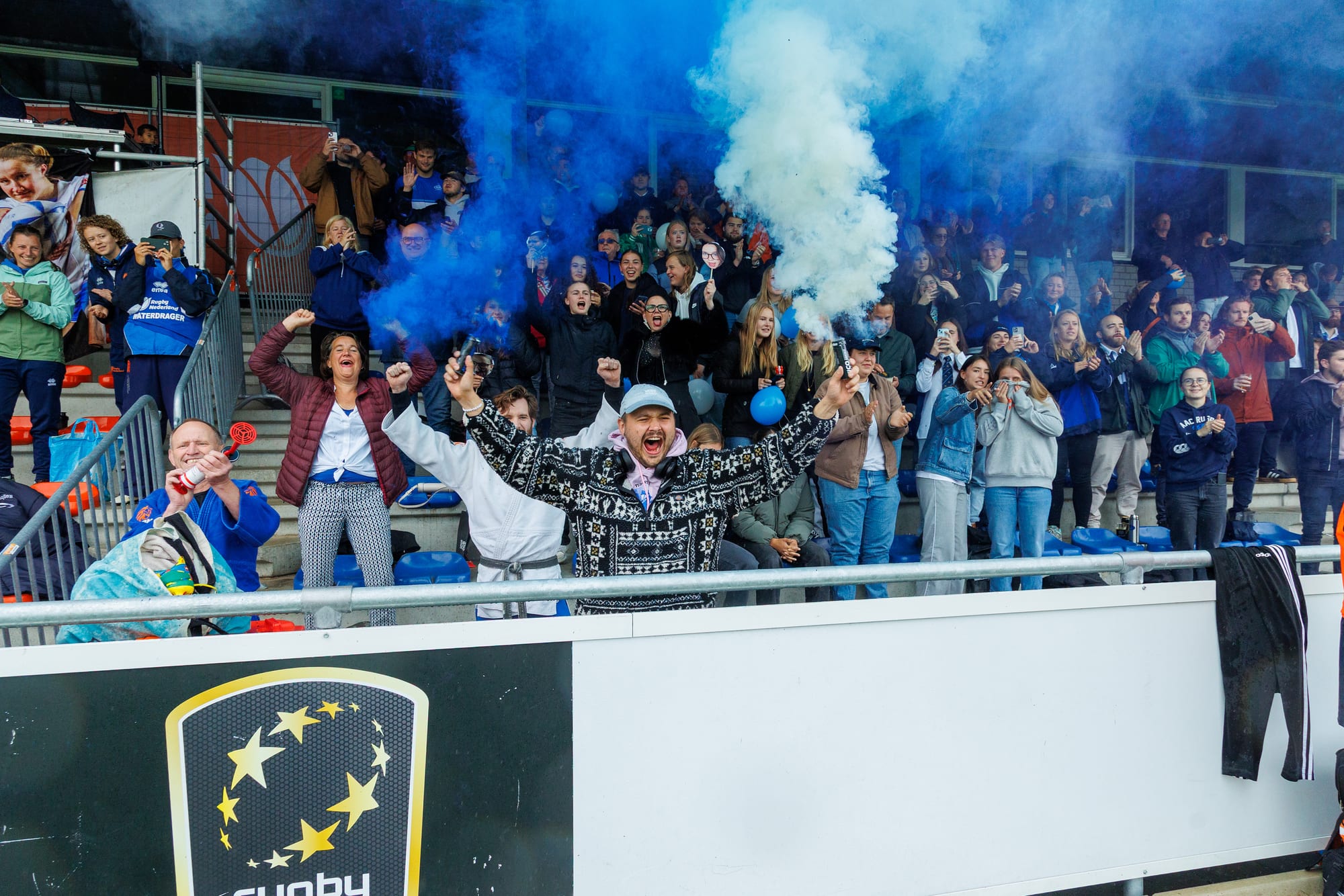 AAC supporters celebrate in the stand amid blue smoke