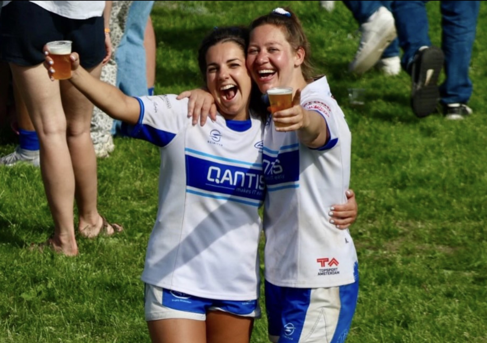 Two AAC women in blue-and-white club kit celebrate together