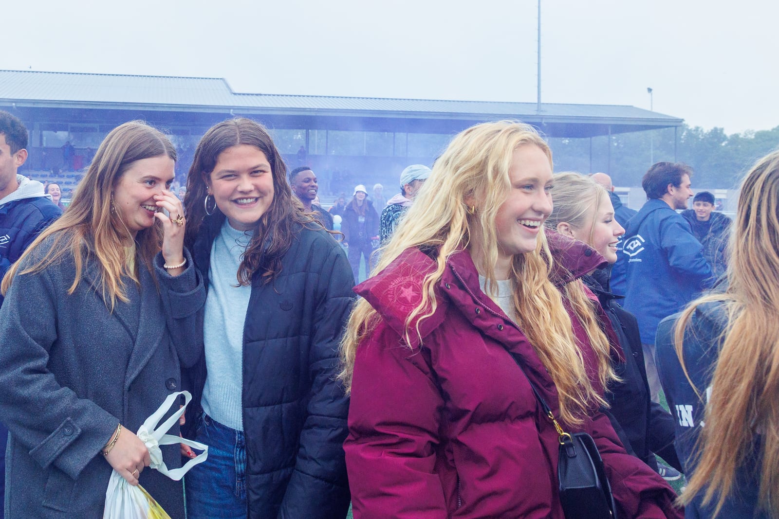 AAC supporters smiling pitchside in the smoke from the post-match flares