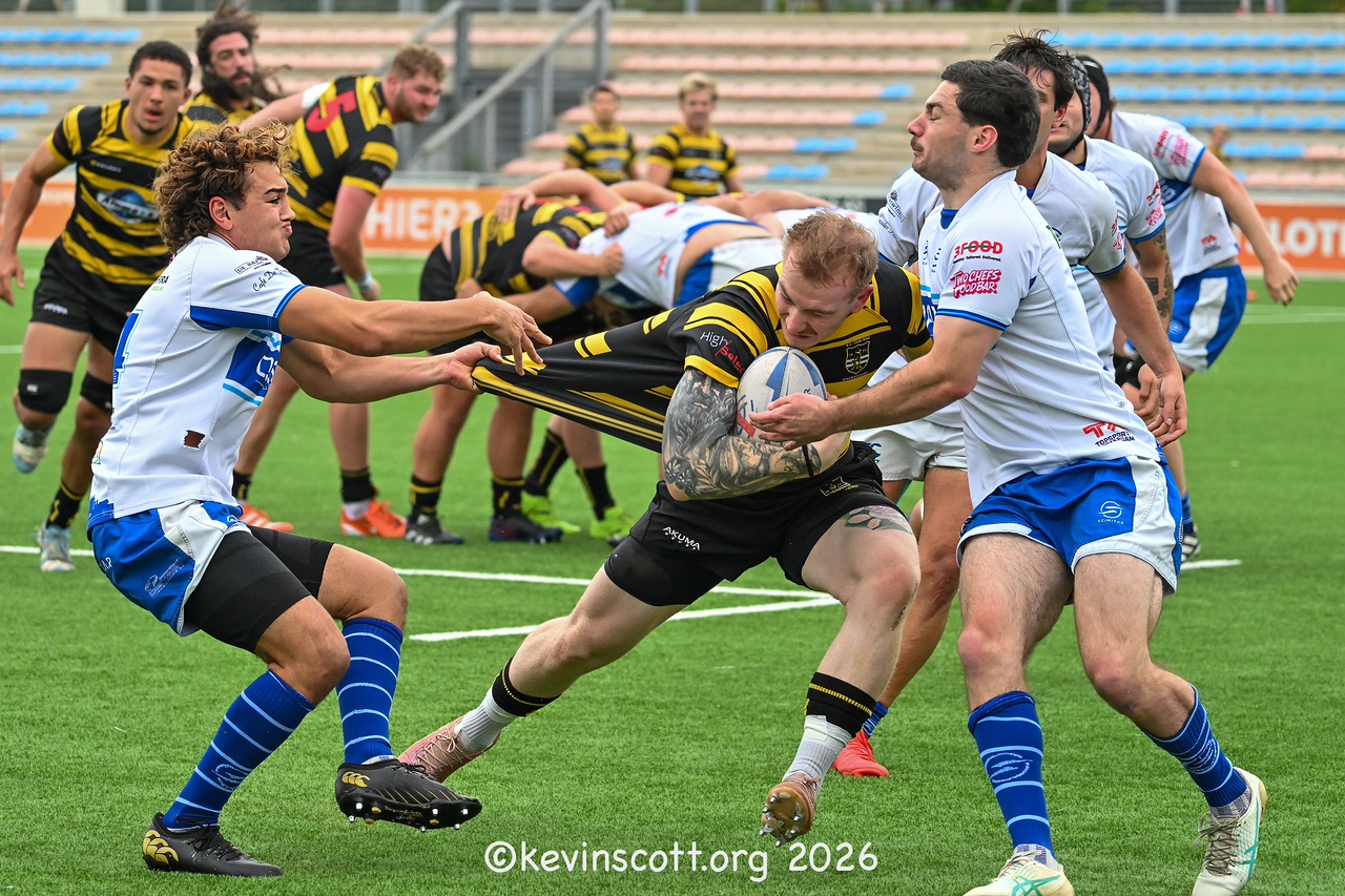 Two AAC players in white-and-blue kit tackle an RC Eemland ball-carrier