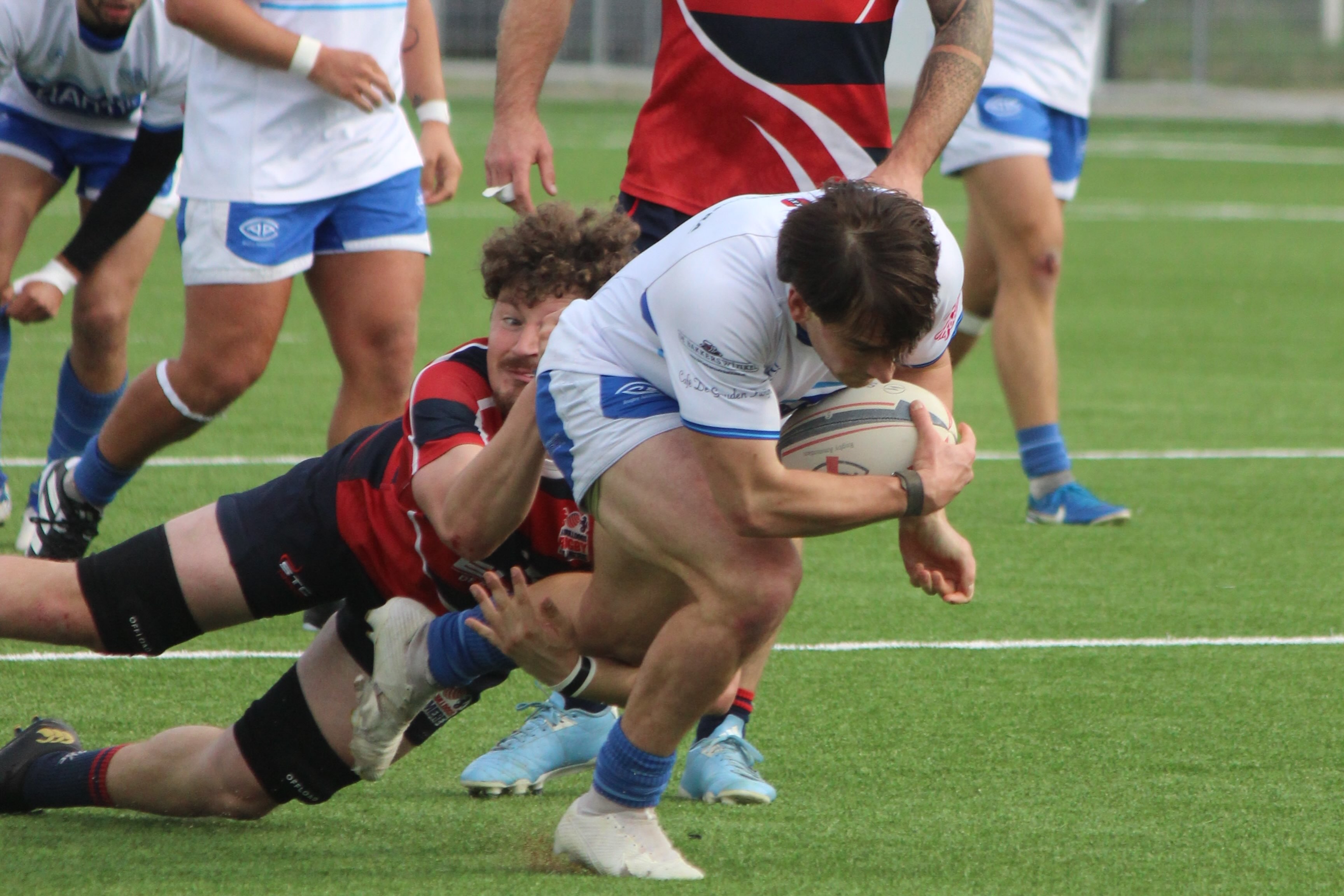 An AAC player in dark blue kit runs with the ball against RC Bulldogs