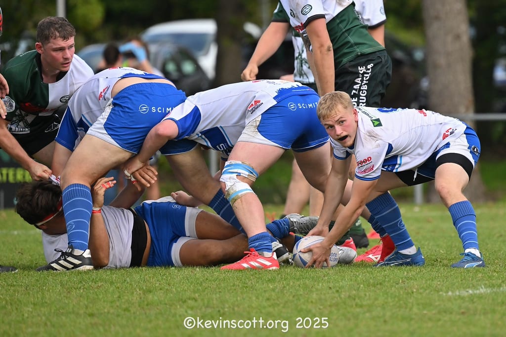 AAC scrum-half in blue and white kit clearing the ball from a ruck, with team-mates protecting possession